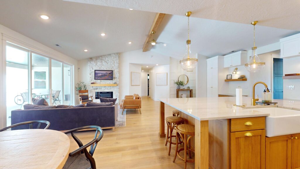 Open-concept home addition with vaulted ceilings, stone fireplace, wood beams, and upgraded kitchen by Archway Construction.
